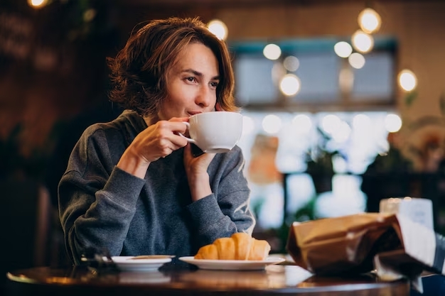 joven-mujer-comiendo-croissants-cafe_1303-20407 cafe saludable